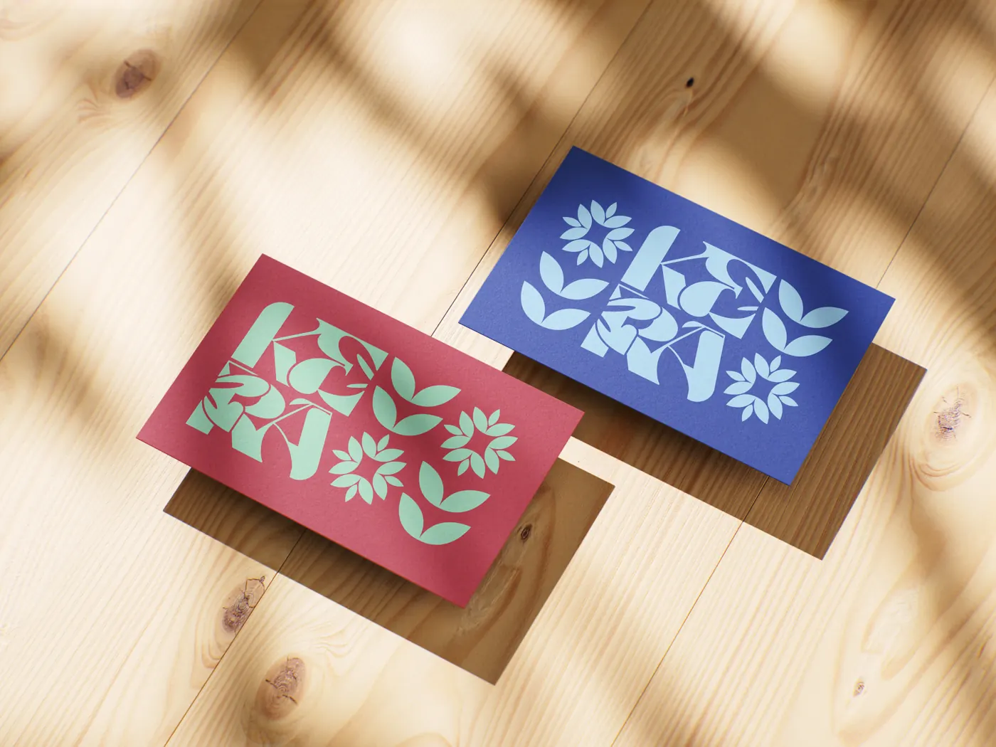 Two KERA business cards on a wooden desk, one red with a mint pattern and one blue with a light-blue pattern