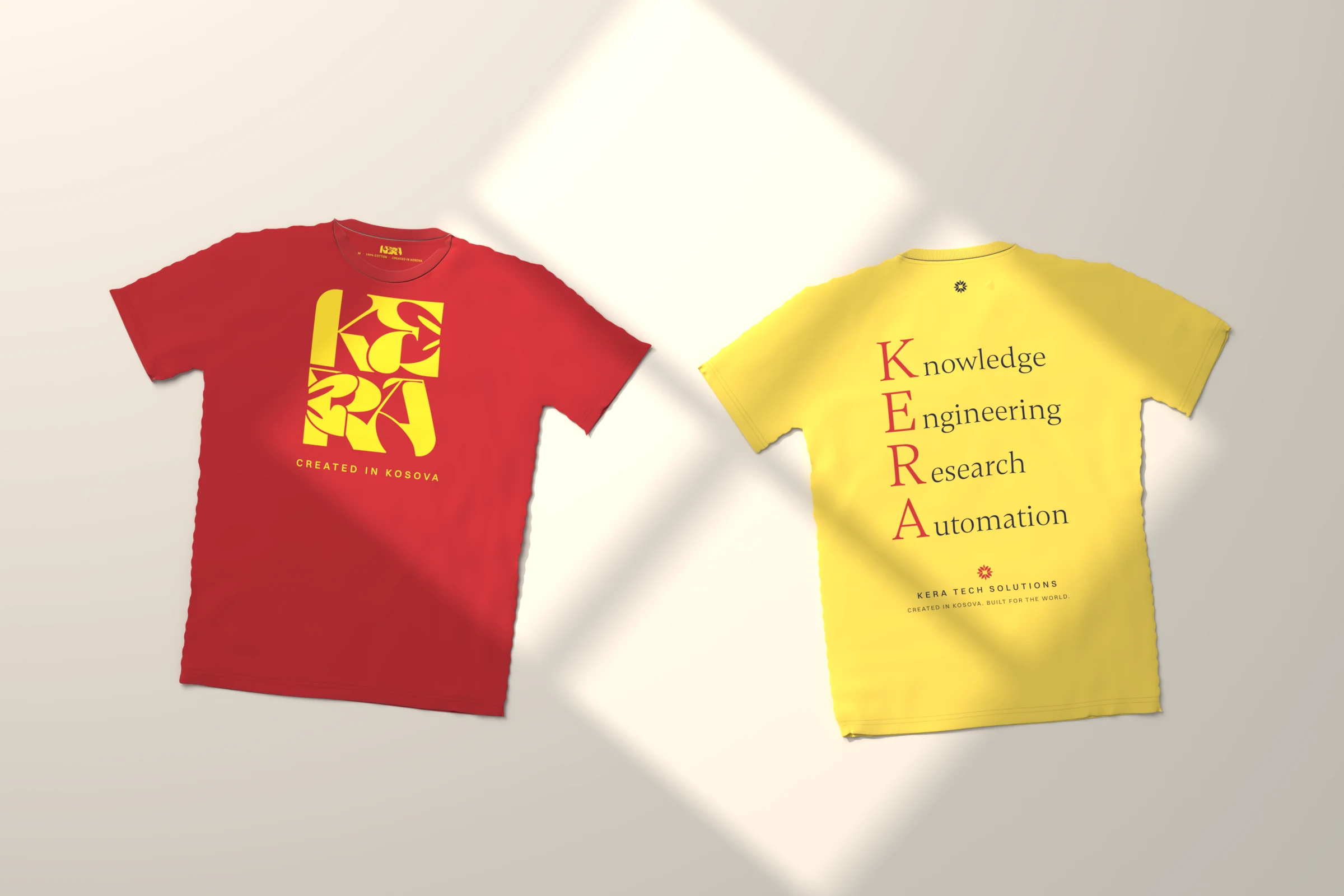Two KERA t-shirts laid flat in window light: a red tee with the yellow stacked KERA mark on the front, and a butter-yellow tee showing its back print, Knowledge, Engineering, Research, Automation, with the initials in red
